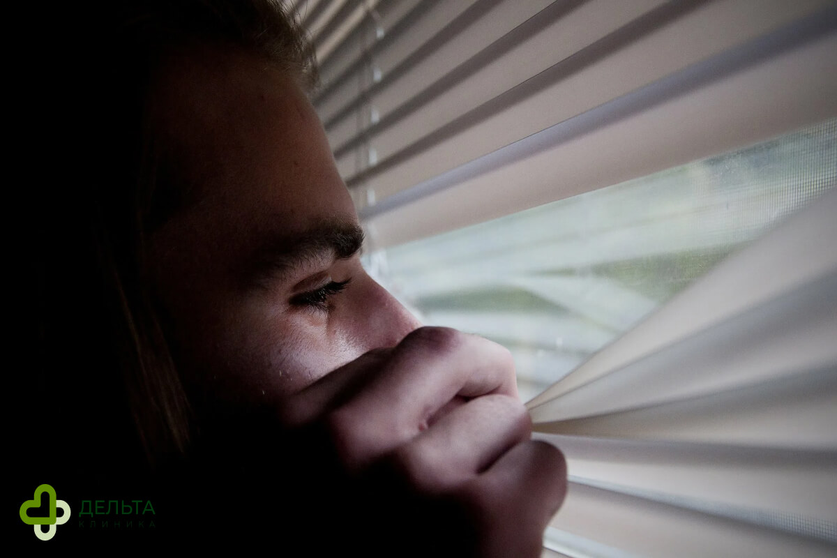 Мужчина смотрит сквозь жалюзи